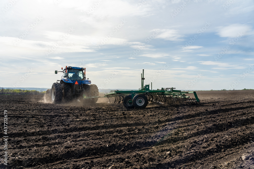 Fototapeta premium A tractor with cultivator plowing on morning.