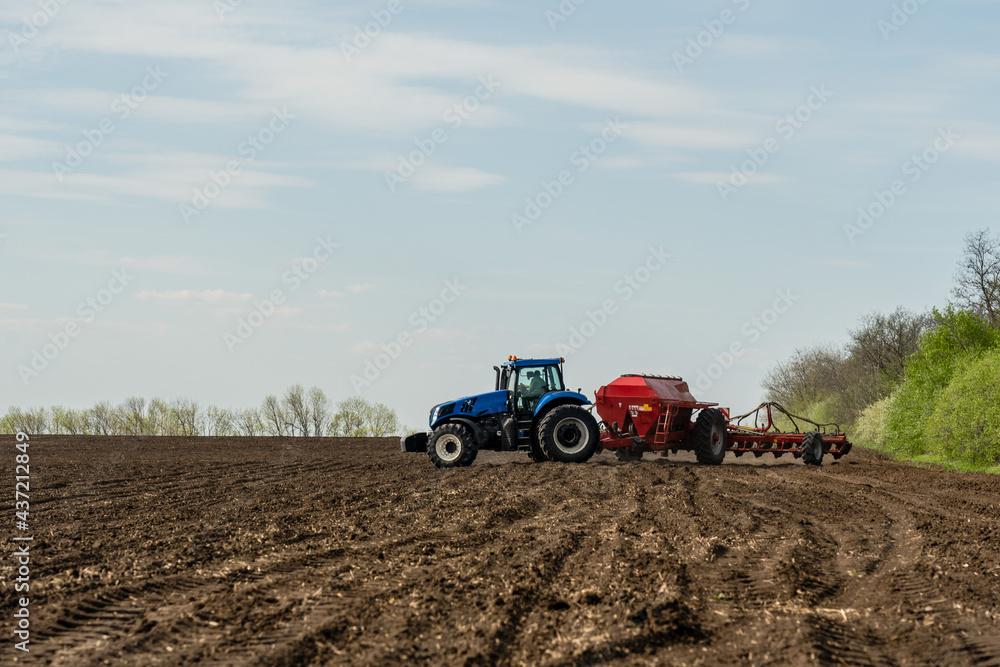 Fototapeta A tractor cultivating field at spring morning.