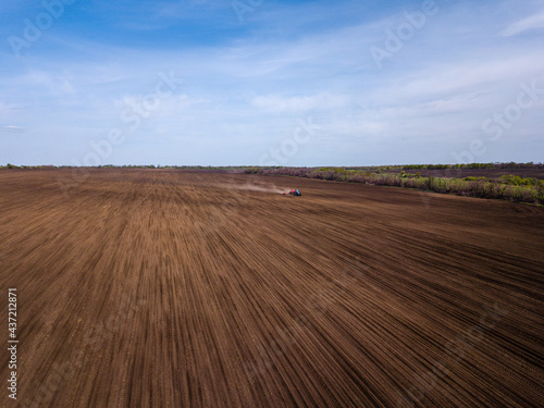 Aerial view of plowing fields by tractor and blue sky