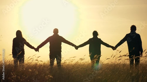 Silhouette Family Teamwork Team People Holding Hands Sunset business team joins hands for business success. Family silhouette together hand in hand. Teamwork of four people for a successful work. photo