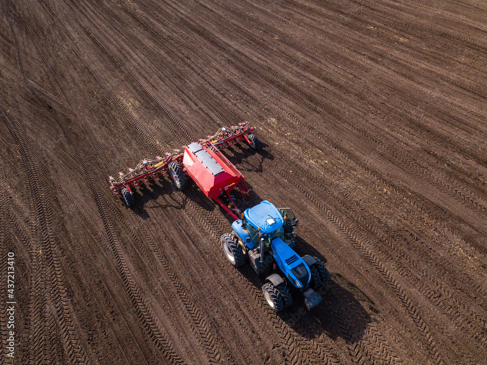 Top view from drone of big tractor with cultivator works on field