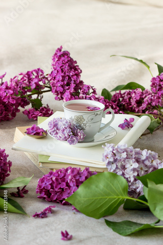 Romantic background with cup of tea ,lilac flowers and open book over white table