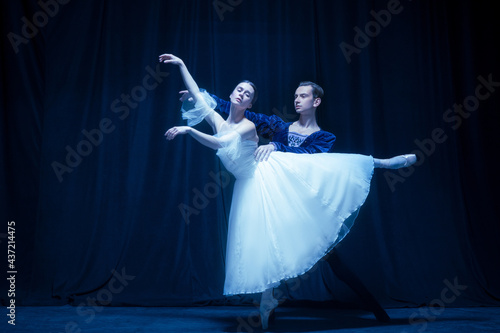 Young woman in wedding dress and man, two ballet dancers in art performance dancing isolated over dark background. photo