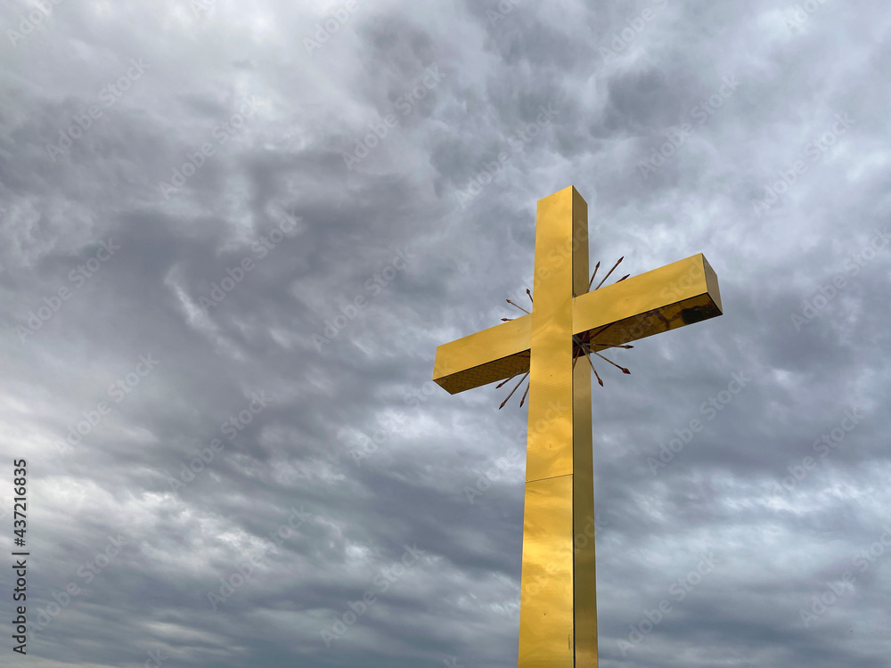 Golden cross on cloudy sky background