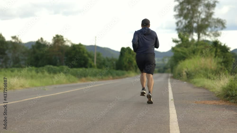 Asia man wearing sportswear running on the road with mountain background. Young man jogging for exercise in the nature. healthy lifestyle and sports concept Asia man wearing sportswear running on the road with mountain background. Young man jogging for exercise in the nature. healthy lifestyle and sports concept