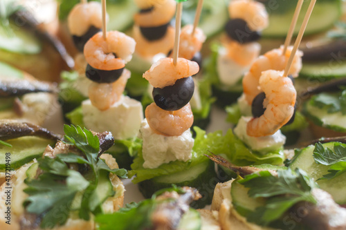 appetizer on skewers with shrimp and sandwiches with sprats and herbs
