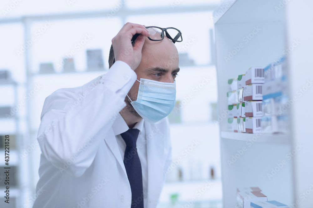 Man pharmacist in protective face mask working in drugstore Man pharmacist in protective face mask working in drugstore