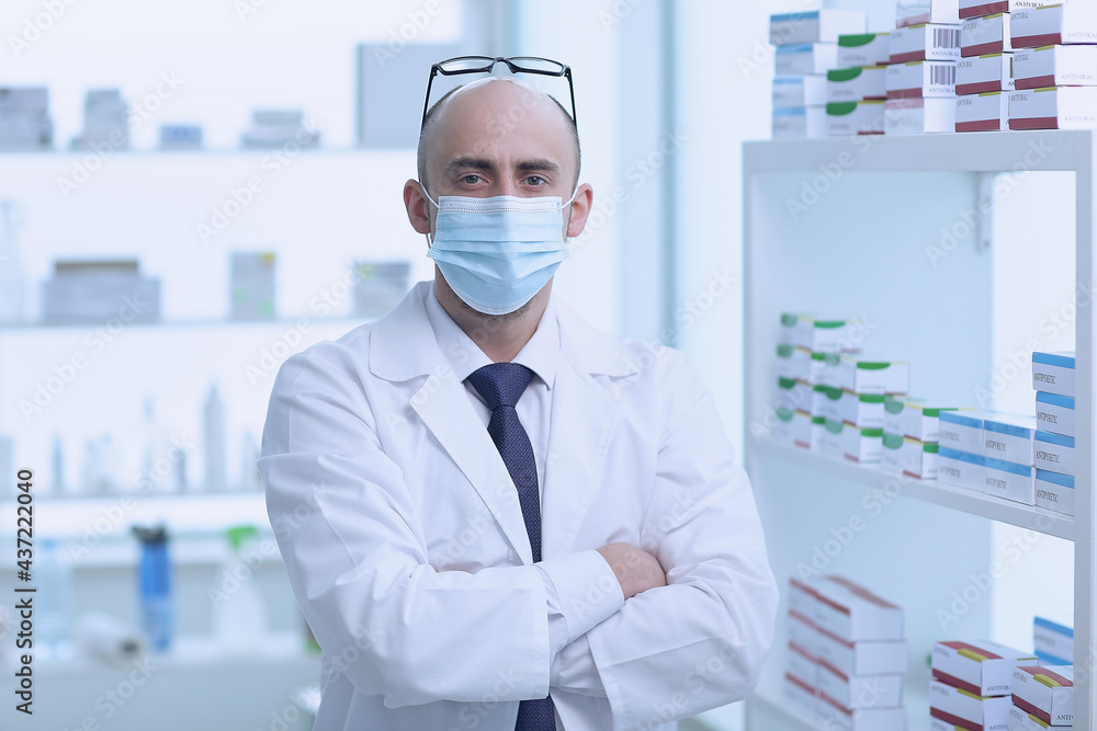 Pharmacist is Working in protective mask. Man Wearing Special Medical Uniform. Located in Pharmacy. Pharmacist is Working in protective mask. Man Wearing Special Medical Uniform. Located in Pharmacy.