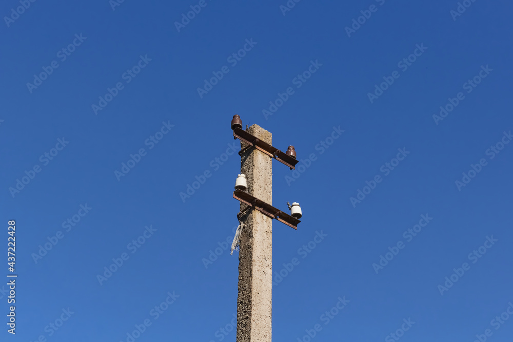 One old electric pole without wires against a blue sky. One old electric pole without wires against a blue sky.