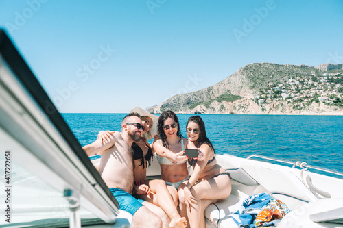 smiling friends sitting on yacht deck taking a selfie with a smartphone © noeliauroz
