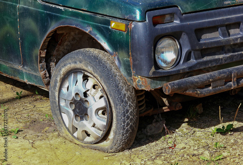 the front wheel of an abandoned green passenger SUV after a serious crash close-up.