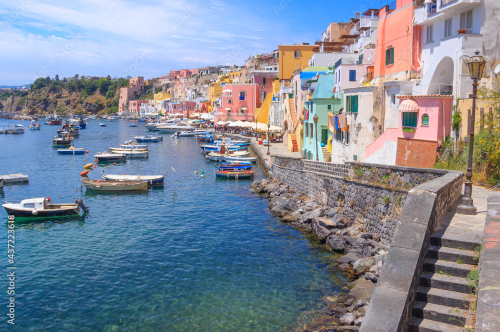 Panoramic view of beautiful Procida, Italian Capital of Culture 2022: colorful houses, cafes and restaurants, fishing boats and yachts in Marina Corricella , in Bay of Naples, Campania, Italy.