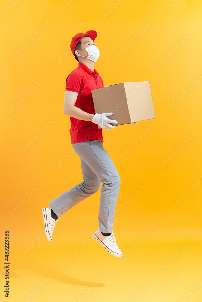delivery man with face mask and gloves holding a cardboard box and jumping delivery man with face mask and gloves holding a cardboard box and jumping