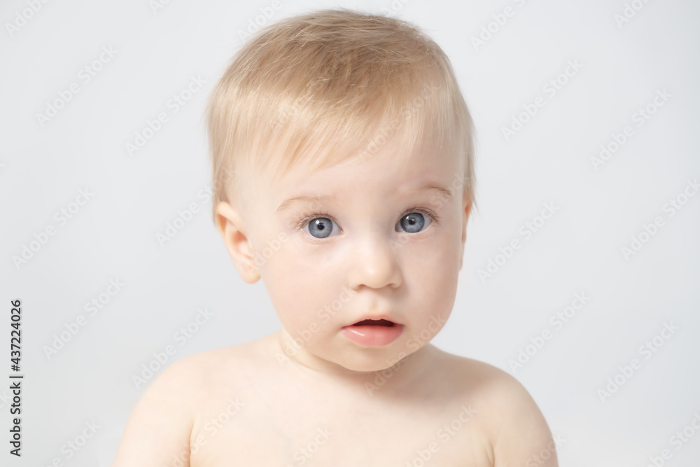 Close-up of beautiful cute adorable blonde caucasian topless baby girl on grey background with open mouth,looking at camera.Healthy kid skin
