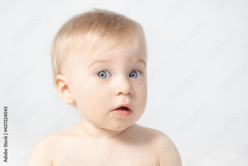 Close-up of amazed beautiful cute adorable blonde caucasian topless baby girl on grey background with open mouth,looking at camera.Healthy kid skin Close-up of amazed beautiful cute adorable blonde caucasian topless baby girl on grey background with open mouth,looking at camera.Healthy kid skin