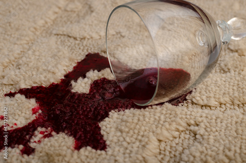 A glass of red wine fell on the carpet, wine spilled on the carpet