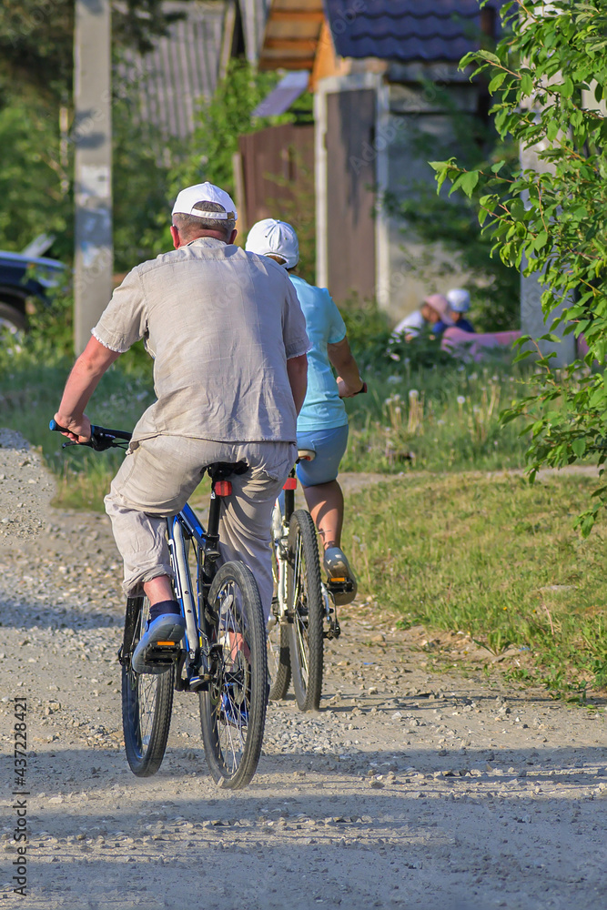 A man and a woman ride bicycles on a rural street on a summer day A man and a woman ride bicycles on a rural street on a summer day