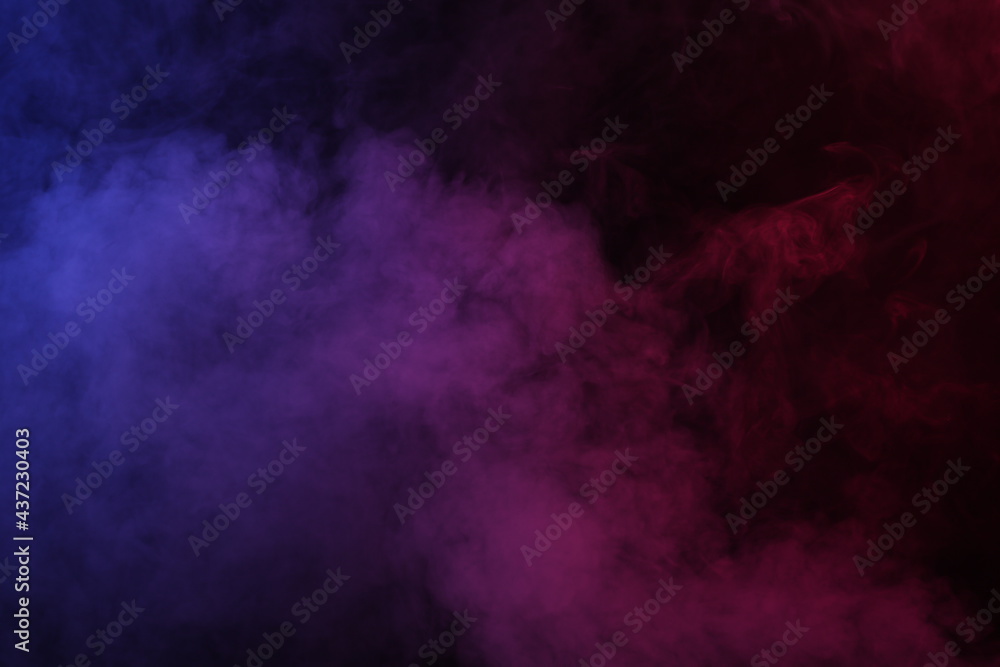 Artificial magic smoke in red-blue light on black background