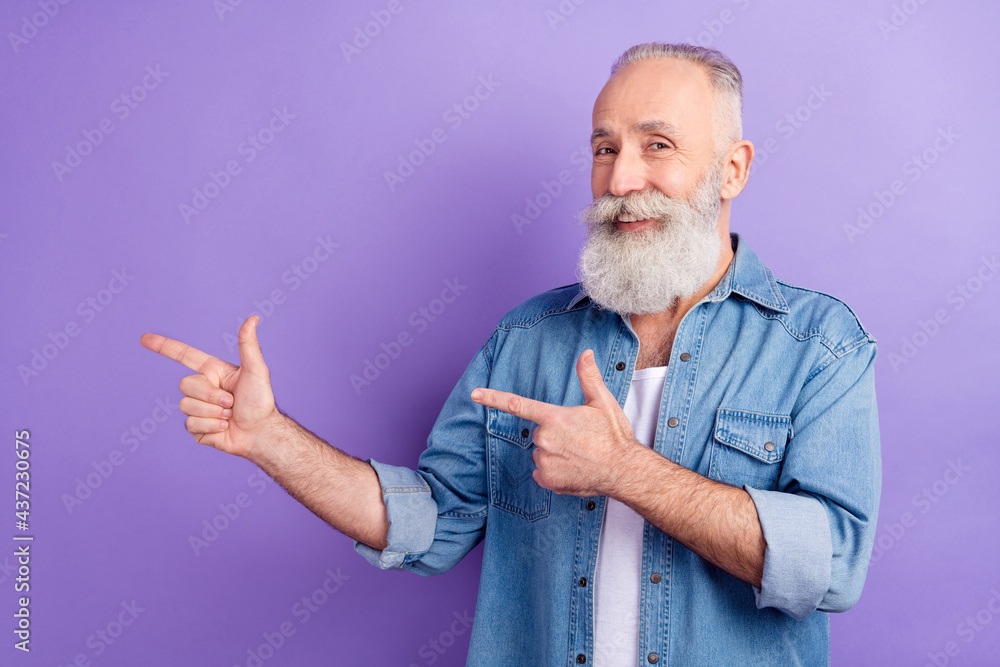 Photo of cheerful positive age gentleman wear jeans shirt pointing two fingers empty space isolated violet color background Photo of cheerful positive age gentleman wear jeans shirt pointing two fingers empty space isolated violet color background