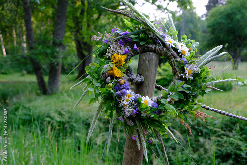 Konstfotografi Colorful wreath of flowers, bent and twigs, hung on a wooden pole during the sum