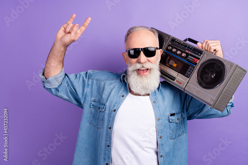 Photo of aged man happy positive smile hold boombox show fingers rock sign isolated over violet color background