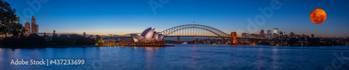 Panoramic night view of Sydney Harbour a full blood moon night and CBD buildings on the foreshore in NSW Australia