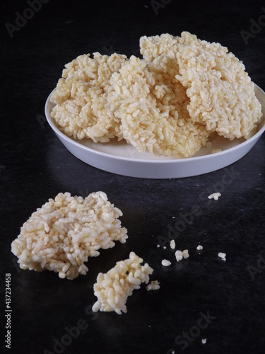 Ranginang or rangginang or rengginang is Indonesian traditional crispy rice or glutinous rice crackers, served in white plate against black background. Kind of deep fried food. 