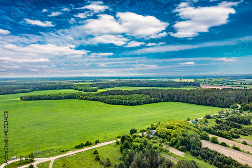Aerial panoramic view of nature. The road in the fields and dense forest. Fields, meadows, road, outside urban nature in Europe. Blue beautiful sky and white clouds. Natural landscape, summer.  © MiaStendal