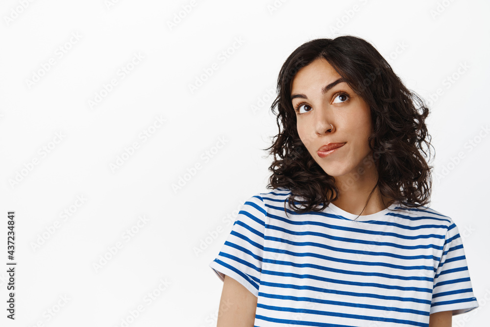 Cute flirty girl daydreaming, imaging something, looking up thoughtful and biting lip silly, picturing or wondering, standing in t-shirt over white background Cute flirty girl daydreaming, imaging something, looking up thoughtful and biting lip silly, picturing or wondering, standing in t-shirt over white background