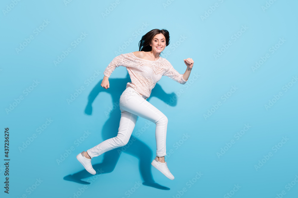Full length profile side photo of happy joyful young lady jump up run sale empty space isolated on blue color background Full length profile side photo of happy joyful young lady jump up run sale empty space isolated on blue color background
