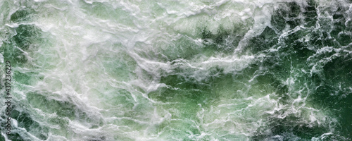 Φωτογραφία Close-up abstract texture above view of river torrent and clear fresh cold water flowing through mountain rocks in valley with foam and bubbles on sunny day