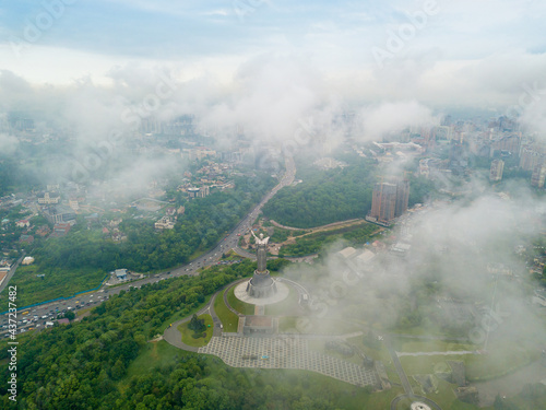 Motherland monument in Kiev between the clouds. Aerial drone view.