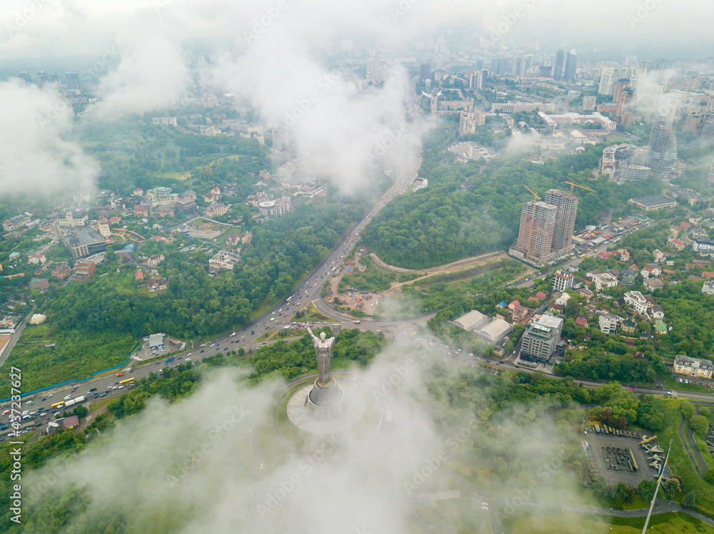 Fototapeta premium Motherland monument in Kiev between the clouds. Aerial drone view.