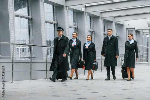 Aircraft crew in work uniform is together outdoors in the airport