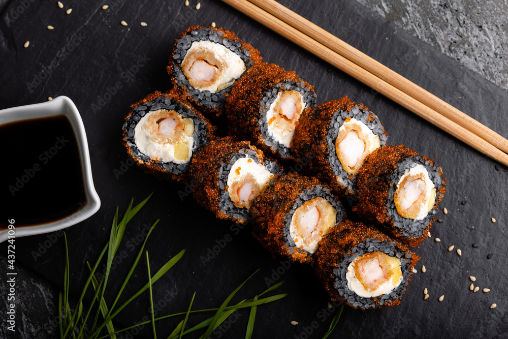 Set of fresh tasty California sushi rolls with black rice on a dark background. Sauce and chopsticks. Set of fresh tasty California sushi rolls with black rice on a dark background. Sauce and chopsticks.