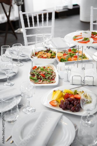  Beautifully set table in the banquet hall of the restaurant. A table with appetizers for wine, cold dishes and salads. White tablecloths and napkins