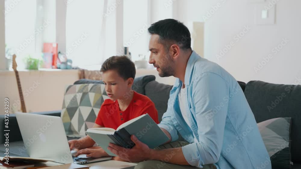 Father helping his son with homework while sitting on the couch in the living room Father helping his son with homework while sitting on the couch in the living room