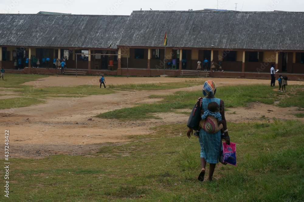 Obraz premium African mother with baby on her back. School courtyard in Takoradi, West Africa. Sekondi-Takoradi, Ghana.