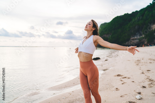 Fit woman with closed eyes feeling alive on sandy beach photo