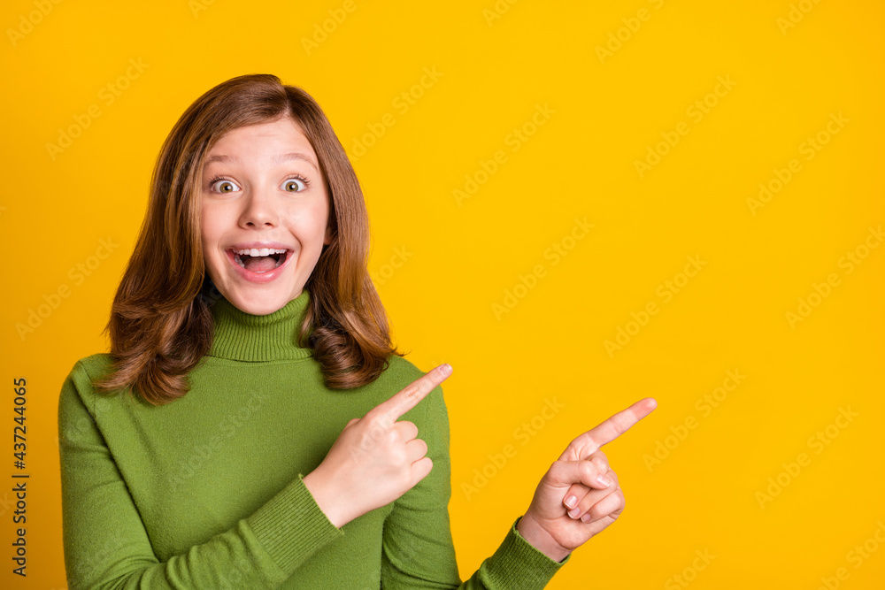 Photo portrait young girl in casual clothes pointing fingers copyspace amazed isolated bright green color background Photo portrait young girl in casual clothes pointing fingers copyspace amazed isolated bright green color background