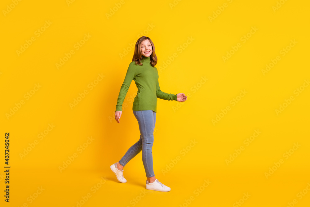 Full length body size photo girl walking forward in casual clothes smiling isolated vivid yellow color background Full length body size photo girl walking forward in casual clothes smiling isolated vivid yellow color background