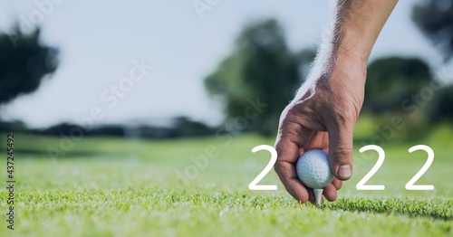 Composition of 2022 number with golf ball placed by man on tee on golf course