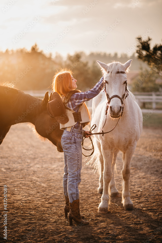 Obraz premium Young woman farmer combing a horse at the ranch.
