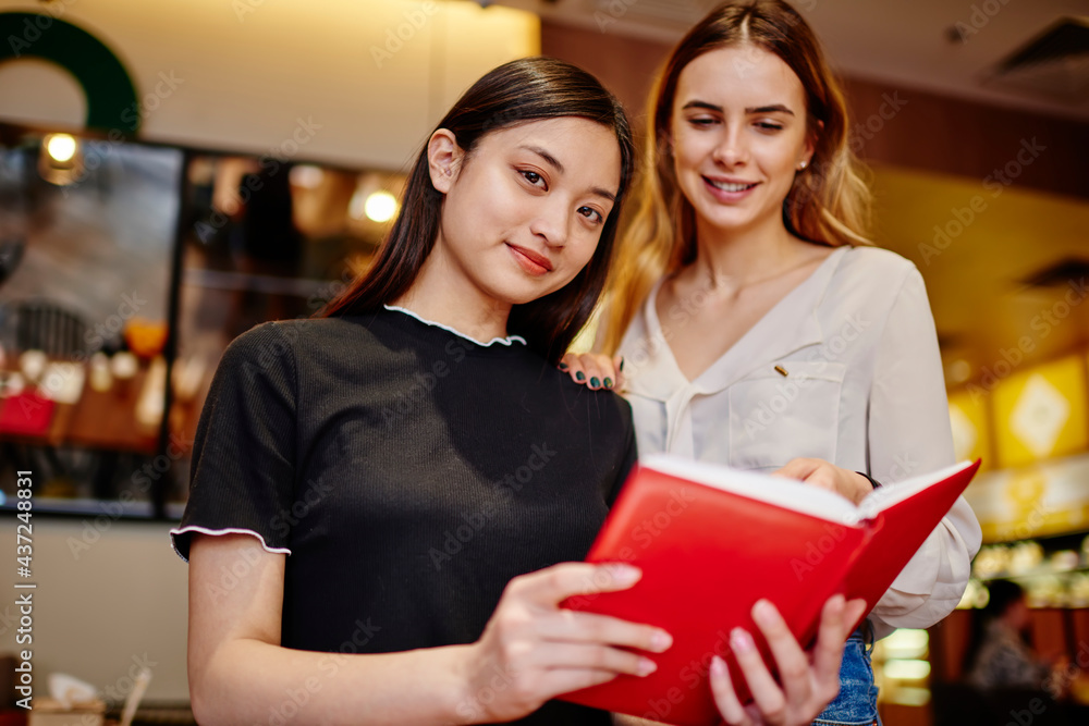 Smiling diverse women with notebook in cafe