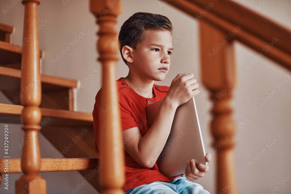 Obraz premium Happy boy playing holding digital tablet and looking away while spending time at home