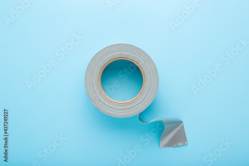 Fototapete One roll of silver cloth duct tape on light blue table background