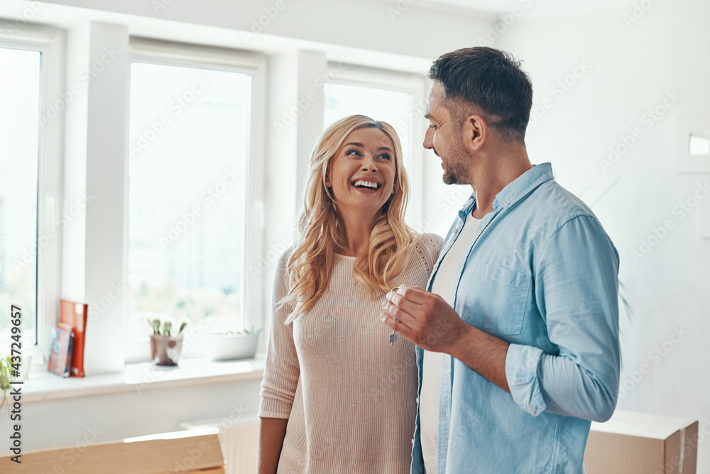 Young beautiful couple in casual wear smiling while receiving keys from new home Young beautiful couple in casual wear smiling while receiving keys from new home