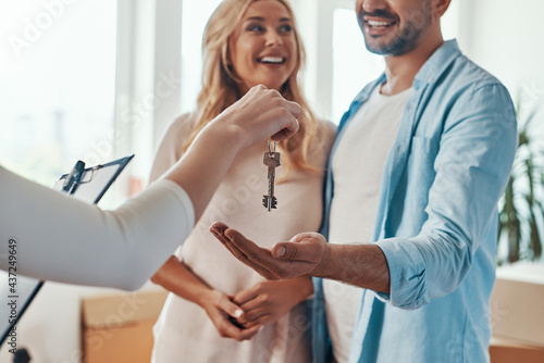 Wallpaper Mural Young beautiful couple in casual wear smiling and embracing while receiving keys from new home Torontodigital.ca