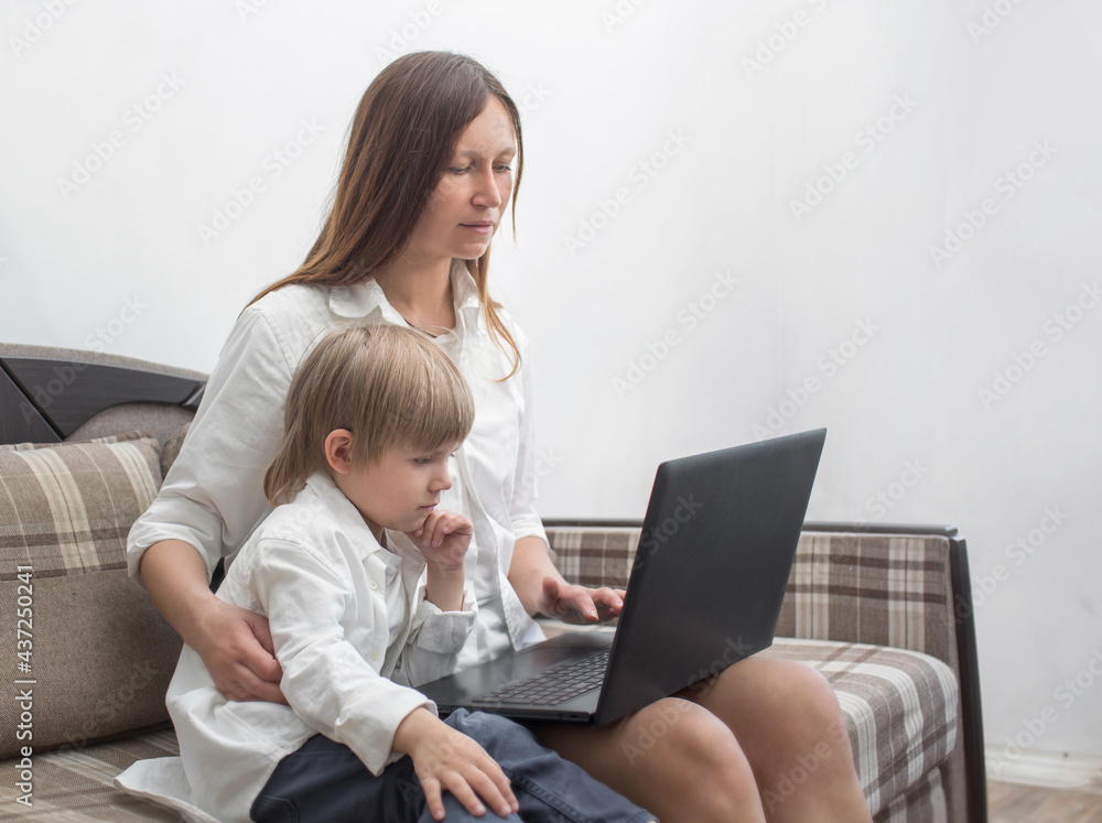Mom teaches her son to use a laptop. The concept of the mother-son relationship Mom teaches her son to use a laptop. The concept of the mother-son relationship