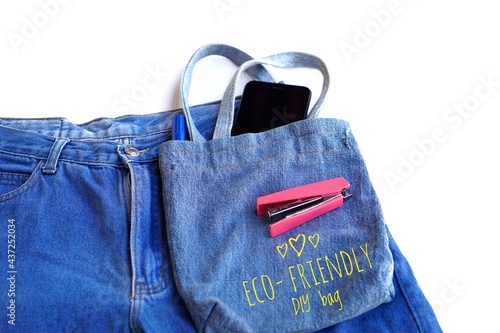 Handmade eco- friendly DIY bag made of old blue jeans on white background. DIY concept. Recycled idea. Reusable bag for groceries and shopping or put things. Eco Friendly. Zero waste. Top view.